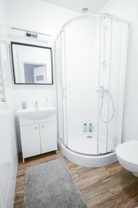 a white bathroom with a shower and a sink at SL apartments in Kraków