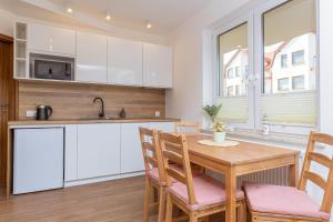 kuchnia z białymi szafkami oraz drewnianym stołem i krzesłami w obiekcie DreamHouse Apartament Baltic Amber Jagiellońska Darłówko Wschodnie w Darłówku