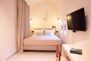 a bedroom with a bed and a tv on a wall at Terra Nera Suites in Perivolos