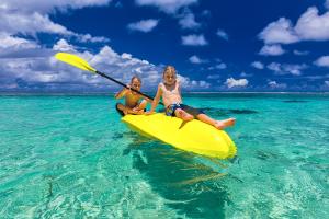 two children sitting on a yellow kayak in the ocean at Bay of Plenty Nature Lodge in Nanuya Lailai