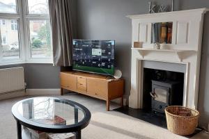 sala de estar con TV y chimenea en Beach House, with BBQ lodge and Hot Tub!, en Bournemouth
