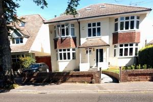 a white house with a car parked in front of it at Beach House, with BBQ lodge and Hot Tub! in Bournemouth