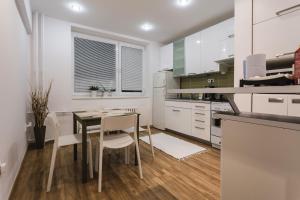 cocina con armarios blancos, mesa y sillas en FLEXIHOME SK - Zborovska - garage Parking with electricity - 2 bedrooms en Košice