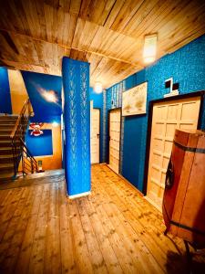 een kamer met blauwe muren, een deur en houten vloeren bij HARABURDI® Recyclart Hotel in Kostelec nad Orlicí
