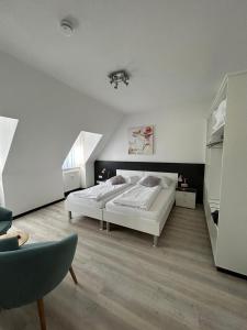 a white bedroom with a bed and a chair at Aparthotel Gartenstadt in Bamberg