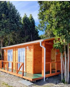 eine Blockhütte mit einer Terrasse und Bäumen in der Unterkunft Cabaña entre árboles Carretera Austral in Puerto Montt