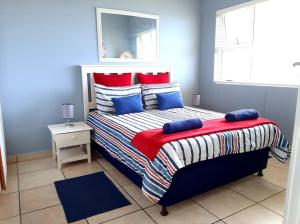 a bedroom with a bed with blue and red pillows at Izinyoni Place, Mangrove Beach Estate in Port Shepstone