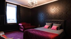 a bedroom with a bed with pink pillows and a chair at A La Villa Perroy les chambres sont spacieuses et les petit-déjeuners offerts in Dunkerque