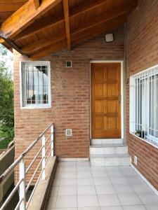 Casa de ladrillo con puerta de madera y escaleras en Departamento de dos dormitorios a una cuadra del lago en Villa Carlos Paz