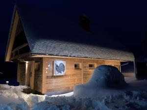 una casa cubierta de nieve con una tabla de snowboard delante de ella en Ein JUWEL "zum-Auerhahn", en Modriach