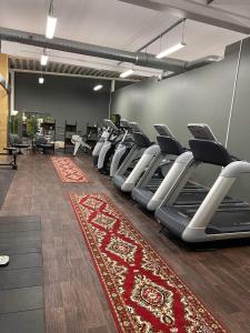 - une salle de sport avec des rames d'appareils de cardio-training et un tapis rouge dans l'établissement Stadshotellet Kristianstad, à Kristianstad