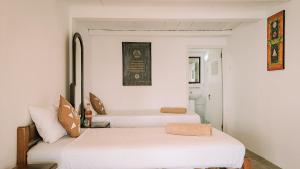two beds in a room with white walls at Welikande Yoga Retreats in Digana