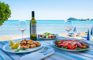 a table with two plates of food and a bottle of wine at Aktypis Beachfront Studios in Laganas