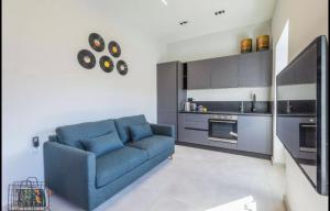 a living room with a blue couch and a kitchen at New - Designer finished 1 Bedroom apartment A 5 minutes ferry away from Valletta in Mosta