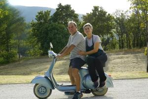 mężczyzna i kobieta siedzący na skuterze w obiekcie Agriturismo Colle Casini Cortesi w mieście Caldarola