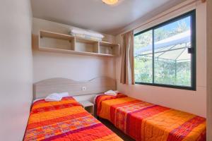two beds in a room with a window at Camping Residence Oliva in Rabac