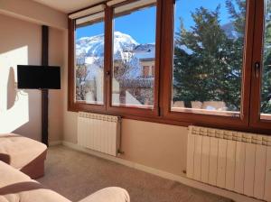 a room with two windows and a view of a snow covered mountain at El Cambaz - tucasaenlospirineos in Panticosa