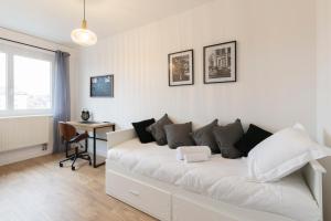 ein weißes Sofa in einem weißen Zimmer mit einem Schreibtisch in der Unterkunft Le Placieux avec parking privé in Nancy