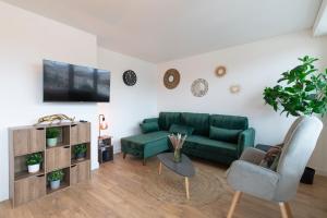 ein Wohnzimmer mit einem grünen Sofa und einem TV in der Unterkunft Le Placieux avec parking privé in Nancy