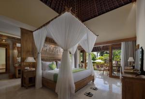 1 dormitorio con 1 cama con dosel en The Alena a Pramana Experience, en Ubud