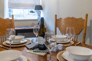 una mesa con una botella de vino y copas. en Cotswold Way Cottage, en Stroud