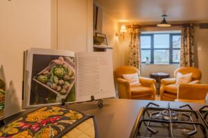 a kitchen counter with a stove and a book at Cotswold Way Cottage in Stroud