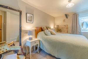 a bedroom with a large bed and a chair at Cotswold Way Cottage in Stroud