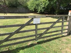 a wooden fence with a dog walking sign on it at Robeanne House Holiday Accommodation in Shiptonthorpe