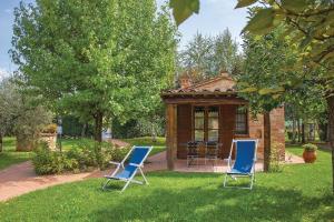 two blue chairs in the grass in front of a gazebo at L'Oasi della Pergola in Castiglione del Lago