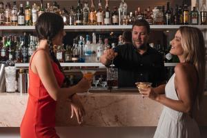 two women standing at a bar with a bartender at Hotel Perrakis in Kipri