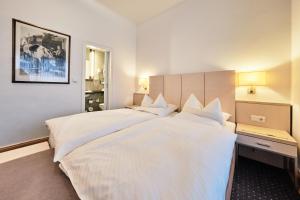 un grande letto bianco in una camera d'albergo di Hotel Haus Berlin a Bonn