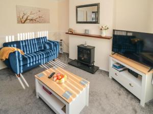 a living room with a blue couch and a tv at Fuschia Cottage in Whitby