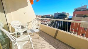 a balcony with white chairs and a view of a city at La Couronne du Cros in Cagnes-sur-Mer