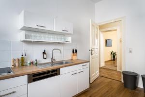 une cuisine avec des armoires blanches et un évier dans l'établissement Super Zentral super schöner Altbau in Moabit Rostockerstraße im Herzen von Berlin für bis zu 6 Personen, à Berlin 9 autres photos