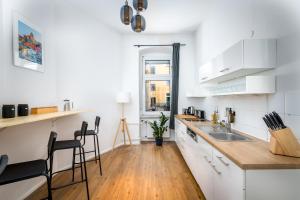 une cuisine avec des armoires blanches et un plancher en bois dans l'établissement Super Zentral super schöner Altbau in Moabit Rostockerstraße im Herzen von Berlin für bis zu 6 Personen, à Berlin