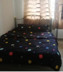 Una cama negra con lunares. en Sobey Laris Homestay RANTAU PANJANG, en Pasir Mas