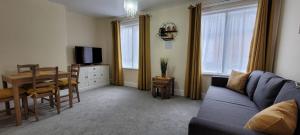 un soggiorno con divano blu, tavolo e TV di Data House Holiday Apartment ad Atherstone
