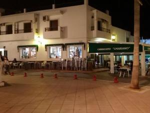 een gebouw met tafels en stoelen ervoor bij Apartamentos EL POSAERO in Carboneras