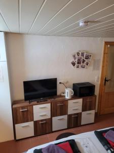 a living room with a flat screen tv on a cabinet at Gästezimmer Haus Talblick in Lautenthal