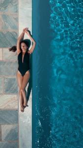 a woman in a black bathing suit standing next to a swimming pool at Hotel Perrakis in Kipri