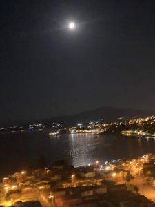 Una luna sobre una ciudad y el agua por la noche en Lindo y acogedor departamento en viña del mar en Viña del Mar
