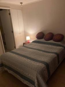 1 dormitorio con 1 cama con almohadas y lámpara en Lindo y acogedor departamento en viña del mar en Viña del Mar