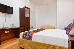 Dormitorio con cama, escritorio y TV en FabHotel Shubh Shaleen Springs, en Bhopal
