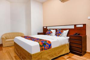 1 dormitorio con 1 cama grande y 1 silla en FabHotel Shubh Shaleen Springs, en Bhopal