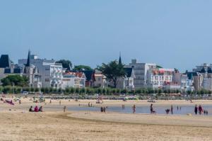 a group of people on a beach with buildings in the background at Chez Margarett in Royan