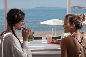two women sitting at a table by the beach at Hotel Perrakis in Kipri