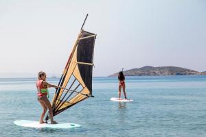 two people on surfboards with a sail on the water at Hotel Perrakis in Kipri