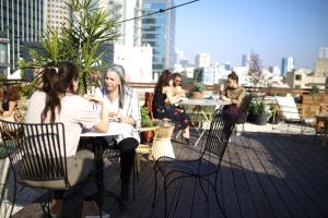 eine Gruppe von Menschen, die an Tischen auf dem Dach sitzen in der Unterkunft Rena's House in Tel Aviv