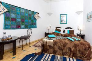 Un dormitorio con una cama y una mesa. en Riad Aquarelle By GE en Marrakech