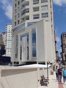 Dos hombres caminando por una acera frente a un edificio. en Apto aconchegante e elegante Morretes itapema, en Meia Praia
